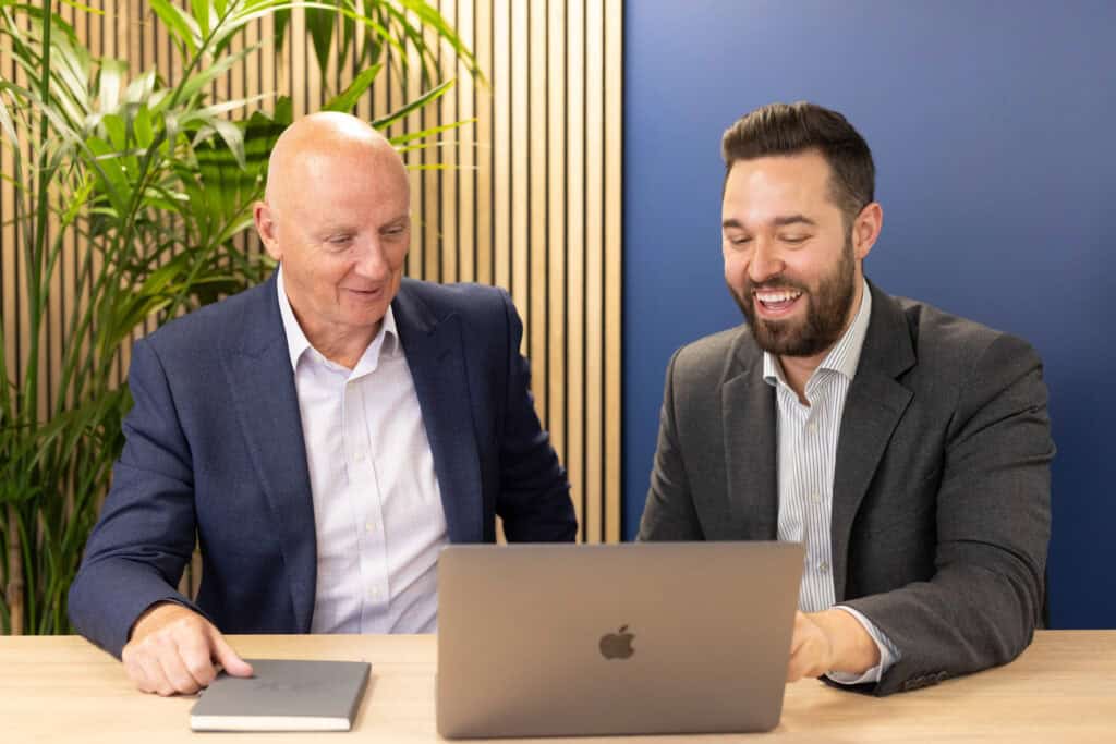 Founder of GLX, Graham Lewis, and Managing Director of GLX, Jack Presland sit at a desk looking at a laptop.