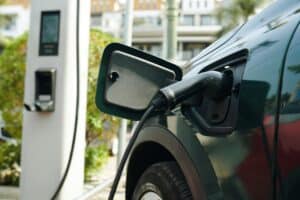 A black electric car with its charging cable plugged in, used as the feature photo for GLX's article to buy or lease a company car.