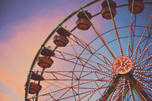 A view of a ferris wheels from the ground looking up at a dusky pink evening sky. This is a decorative photo for the temporary 5% VAT rate for summer 2026 GLX blog post.